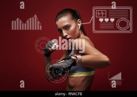 Ritratto di giovane bella sportive indossando guanti di allenamento. Ella è pronta per la lotta contro un avversario. Isolato su sfondo rosso Foto Stock