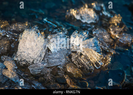 Pezzi di ghiaccio in fusione sotto il luminoso sole di primavera sulla riva del fiume. Messa a fuoco selettiva di ripresa macro con DOF poco profondo Foto Stock