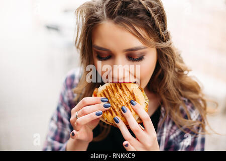 Buongustai con hamburger cercando riposo con espressione sconvolta. Foto Stock