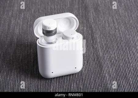 Wireless bluetooth cordless auricolari con custodia a pagamento su un sfondo di tessuto Foto Stock