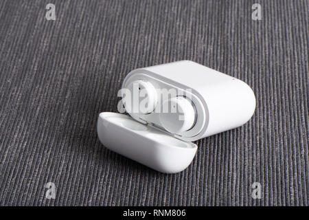 Wireless bluetooth cordless auricolari con custodia a pagamento su un sfondo di tessuto Foto Stock