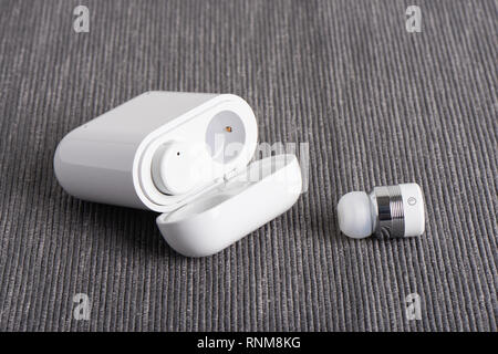 Wireless bluetooth cordless auricolari con custodia a pagamento su un sfondo di tessuto Foto Stock