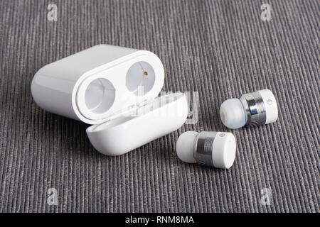 Wireless bluetooth cordless auricolari con custodia a pagamento su un sfondo di tessuto Foto Stock