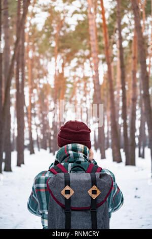 Escursionismo persona di sesso maschile in inverno foresta. Uomo in inverno a scacchi shirt passeggiate in splendidi boschi innevati Foto Stock