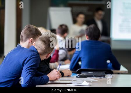 Il brainstorming, giovani studenti di 18-20 anni, vividamente discutere la lezione degli insegnanti al tavolo, prendere un esame, scrivere e rispondere questio di controllo Foto Stock