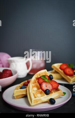 La colazione casalinga cialde belghe con bacche on dark moody sfondo, il fuoco selettivo Foto Stock