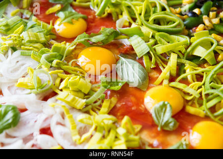 Pizza cruda con uova, porro, ketchup, la cipolla, il basilico e altri ingredienti Foto Stock