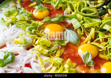 Pizza cruda con uova, porro, ketchup, la cipolla, il basilico e altri ingredienti Foto Stock