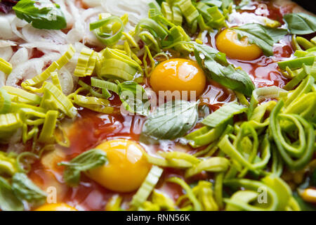 Pizza cruda con uova, porro, ketchup, la cipolla, il basilico e altri ingredienti Foto Stock