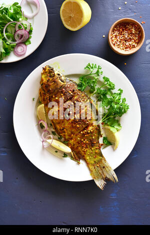 Pesce arrosto su piastra su pietra blu sullo sfondo. Frutti di mare. Vista superiore, laici piatta Foto Stock