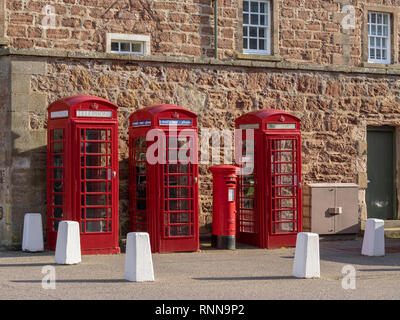 Tre British telefono rosso scatole o chioschi e uno rosso casella postale o pilastro box, Fort George, vicino a Inverness, Scotland Foto Stock