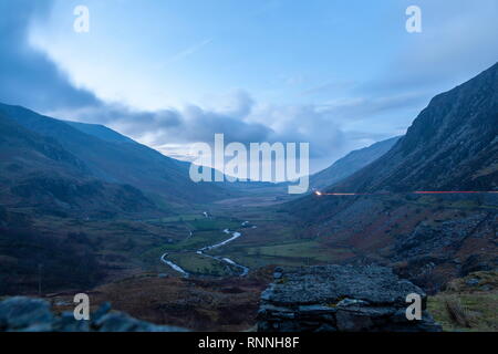 Guardando verso il basso di Nant Ffrancon verso Bethesda con auto sentieri di luce essendo visto sulla A5 trunk road. Parco Nazionale di Snowdonia Foto Stock