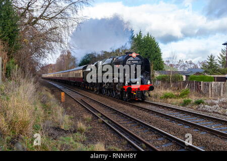 La British Railways (BR) Standard di Classe 7 numero 70000 Britannia passa Weston Ryhn passaggio a livello mentre su una speciale carta. Foto Stock