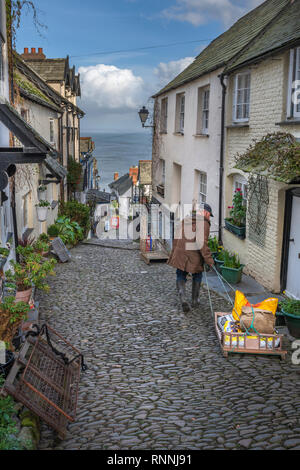 Un uomo offre forniture invernali da una tradizionale slitta per i residenti in High Street a Clovelly in North Devon. Impostare in una ripida collina, sled Foto Stock