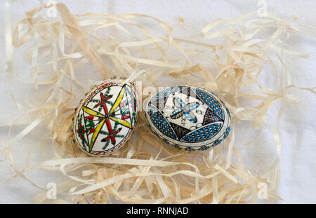 Due tradizionali fatti a mano le uova di Pasqua in paglia sul panno bianco. Modello tradizionale da Bucovina Foto Stock