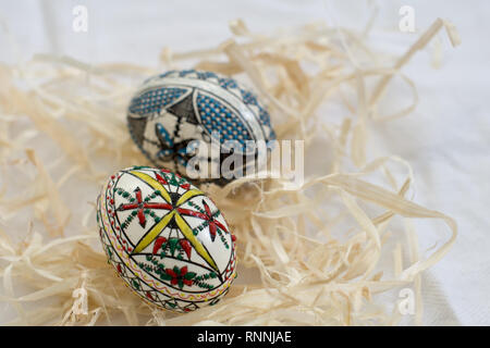 Due tradizionali fatti a mano le uova di Pasqua in paglia sul panno bianco. Modello tradizionale da Bucovina Foto Stock