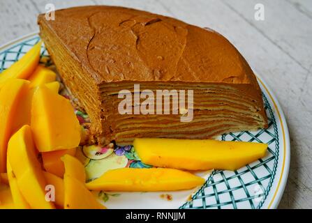 Fetta di strato vegano crêpe dolce con ripieno di cioccolato e coulis di mango Foto Stock