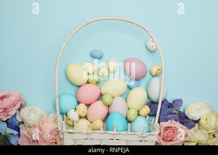 Vista superiore della pasqua pollo e uova di quaglia con cesto di paglia e fiori Foto Stock