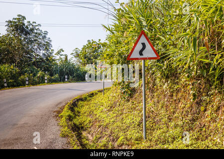 Segno tortuosa strada su una strada di montagna, avvertimento segno di traffico Laos Foto Stock