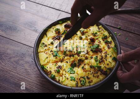 Dhokla fatti in casa - cotto a vapore di farina di ceci torta dal Gujarat, India il fuoco selettivo Foto Stock