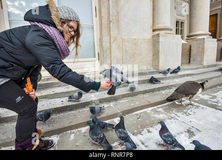 Giovane donna alimentando un piccione al Palazzo Lazienki a Varsavia, Polonia Foto Stock