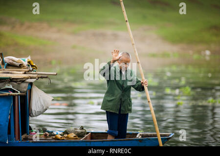 Senior adulto uomo in piedi su una barca in un fiume. Foto Stock