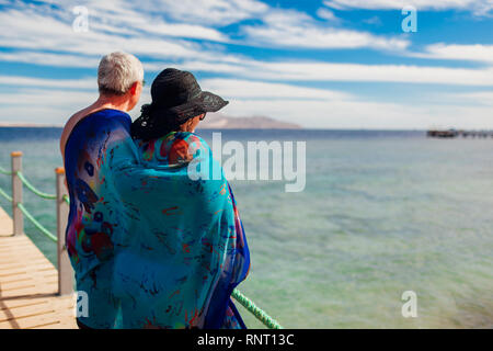Coppia senior camminando sul molo per mare rosso coperto con pareo. Felici le persone che si godono la vacanza. Il giorno di San Valentino Foto Stock