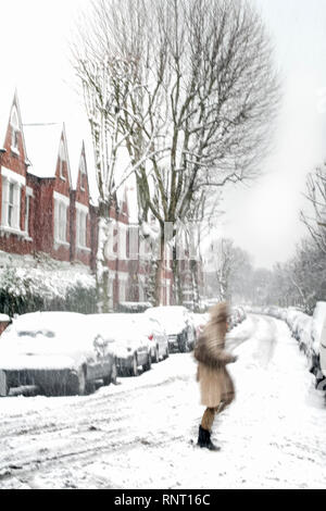 Movimento immagine sfocata di una singola persona sfidando una tempesta di neve in una zona residenziale di Islington, a nord di Londra, Regno Unito Foto Stock