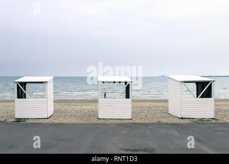 Tre bianco pubblico in legno cabine sulla spiaggia di ciottoli a Weymouth Dorset, Regno Unito, su un nuvoloso giorno di estate Foto Stock