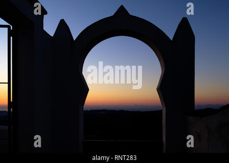 Arco moresco di sunrise in cima della montagna villaggio di Comares, Axarquia, Malaga, Spagna Foto Stock
