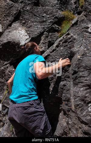 Giovane uomo caucasico è arrampicata su una roccia in Svizzera Foto Stock