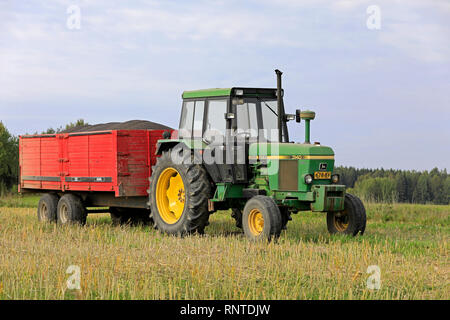 Salo, Finlandia - 8 Settembre 2018: John Deere 3140 trattore e rimorchio agricolo pieno di colza raccolti su di una bella giornata d'autunno. Foto Stock