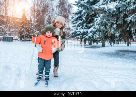 Bella e giovane madre insegna a sciare, Little Boy 3-5 anni, figlio di abbigliamento invernale. In inverno, nella foresta del resort dove c'è un Foto Stock