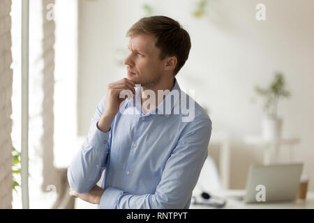 Imprenditore gravi in piedi in ufficio pensando di prendere una decisione Foto Stock