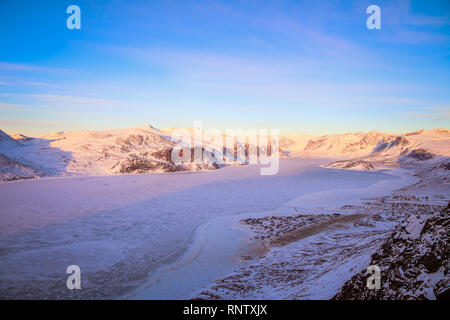 Da dietro la collina di Pangnirtung sono viste sopra il ghiaccio congelato che conducono attraverso il fiordo su Auyuittuq National Park. Foto Stock