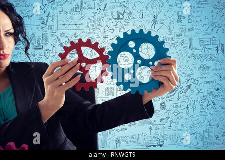 Imprenditrice tenta di collegare pezzi di ingranaggi. Concetto di lavoro di squadra, partnership e integrazione Foto Stock