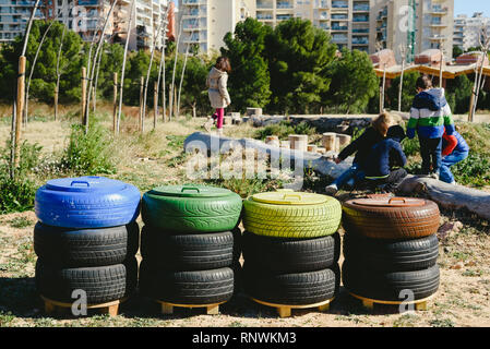 Bambini che giocano attorno a cassonetti per il riciclaggio realizzate con materiali di riutilizzo. Foto Stock