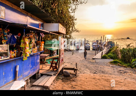 Panajachel, lago Atitlan, Guatemala - 29 dicembre 2018: Al lago stores & jetty con ombra di San Pedro vulcano in golden ora haze dietro. Foto Stock