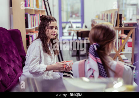 Grave bellissima ragazza con due panini a guardare sul suo parlare amico Foto Stock