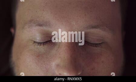Chiudere gli occhi del giovane uomo felice esaminando la lente della fotocamera Foto Stock