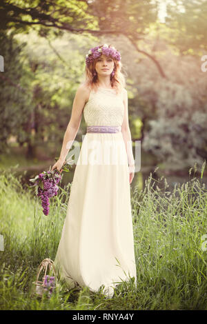 Bella Donna con fiori all'aperto su erba verde sfondo in primavera giornata romantica Foto Stock