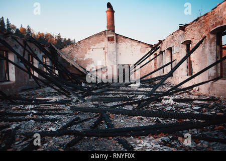 Bruciato casa in legno. Casa dopo l'incendio. Bruciò Mattone casa con tetto bruciato vista interna Foto Stock