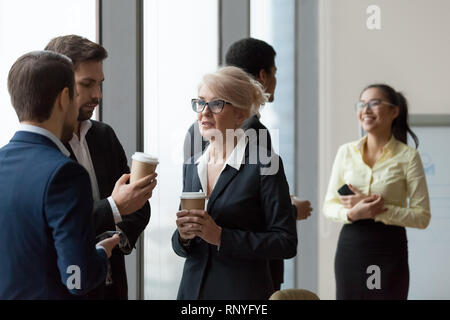 Diversi i lavoratori aventi la conversazione in piedi in ufficio in pausa di lavoro Foto Stock