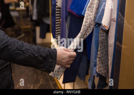 Maschio lato scegliendo una camicia nel negozio Foto Stock