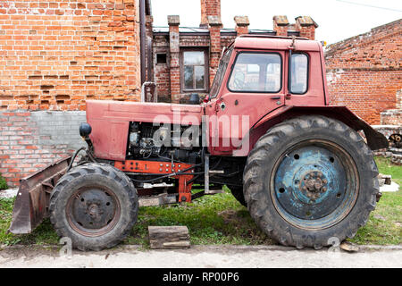 Il vecchio trattore rosso sull'azienda. Foto Stock