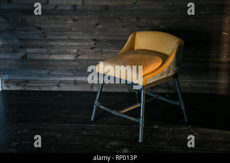 Sgabello in metallo con morbido rivestimento in stile loft contro una parete in legno. Spazio libero per il testo. Foto Stock