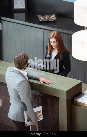 Imprenditore in piedi presso hotel il banco di ricevimento Foto Stock
