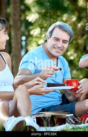 Famiglia avente gli alimenti durante il picnic Foto Stock