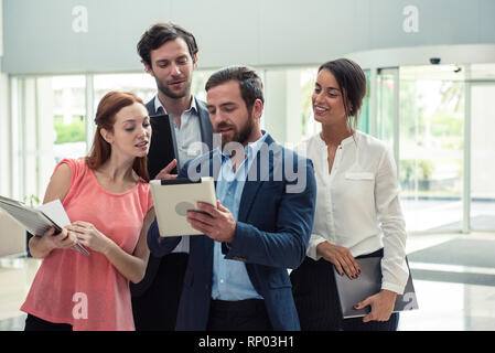 Architetti discutendo su tavoletta digitale nella hall hotel Foto Stock