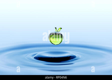 La pioggia caduta nella forma di mela verde caduta sul blu superficie di acqua Foto Stock